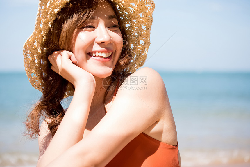 泳装的一名妇女坐在海滩图片