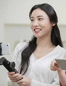 拿着手机拍视频的年轻女子图片