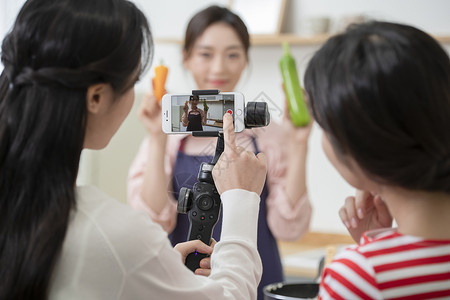 拍摄烹饪做菜短视频的年轻女子高清图片