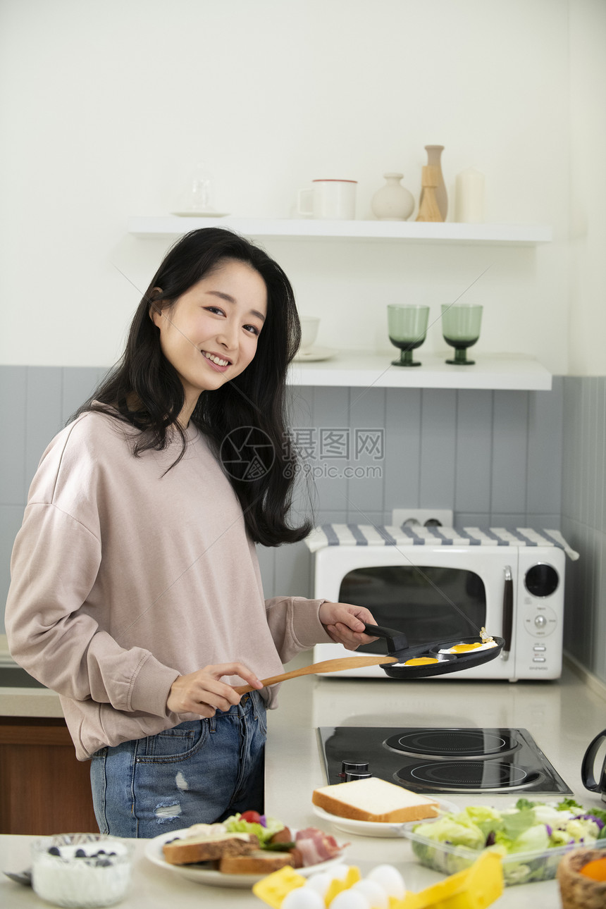 厨房煎鸡蛋的青年女子图片