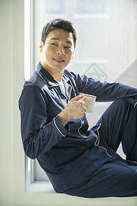成年男子坐在窗边喝咖啡背景图片