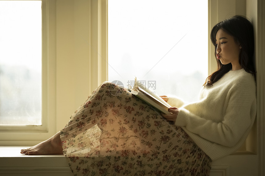 窗边看书的年轻女子图片