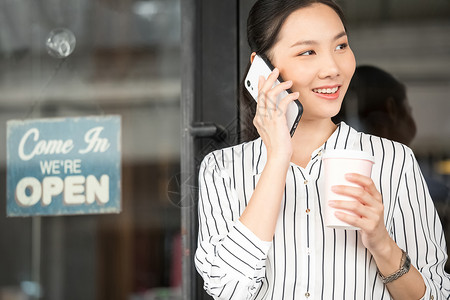 拿着咖啡接听电话的商务女性图片