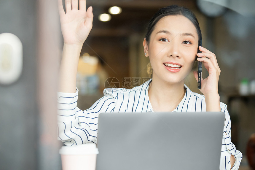 接听电话伸手打招呼的商务女性图片