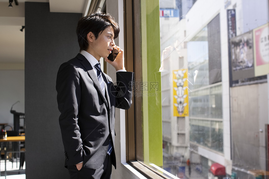 窗边接听电话的商务男士图片