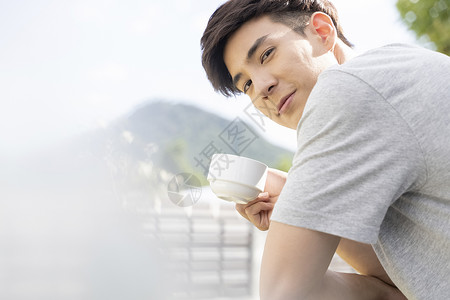 阳台喝咖啡的青年男士图片