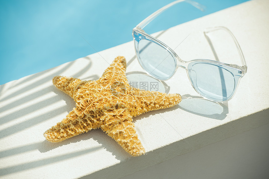 放在游泳池边上的海星和太阳眼镜图片