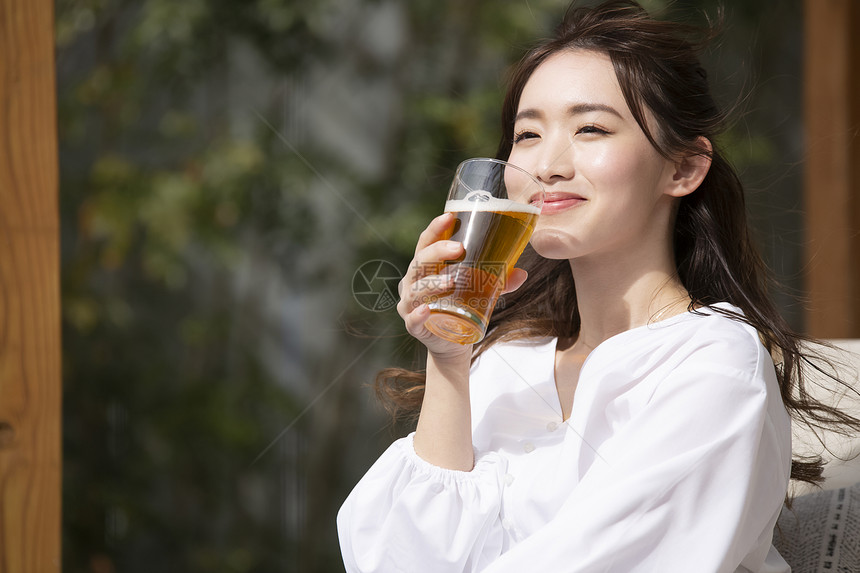 户外喝啤酒的青年女子图片