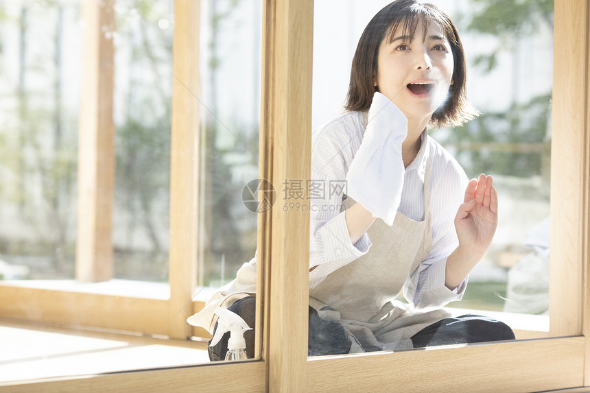 居家清洗窗户玻璃的年轻女子图片