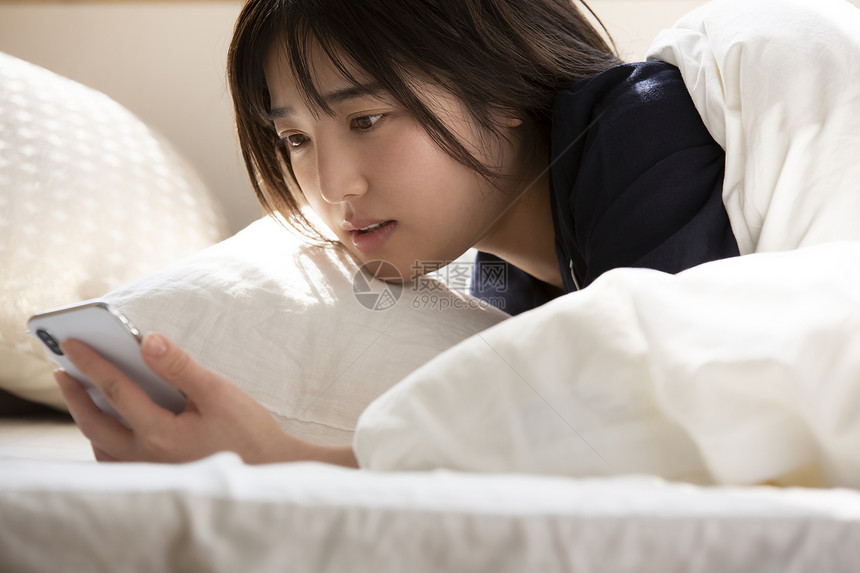 床上拿着手机的年轻女子图片