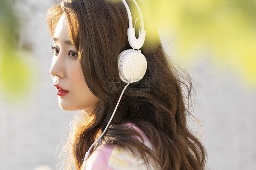 户外戴着耳机听音乐的年轻女子图片