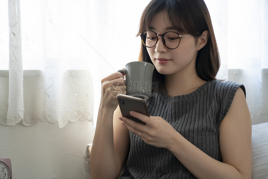 喝咖啡玩手机的年轻女子图片