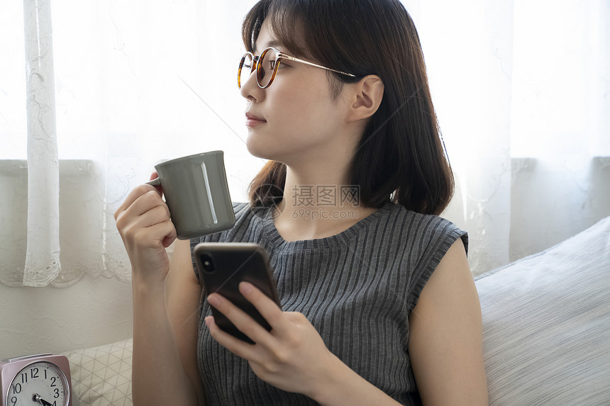 喝咖啡玩手机的年轻女子图片