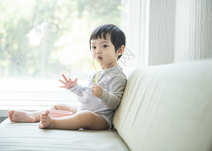 坐在沙发上拿着勺子的小孩图片