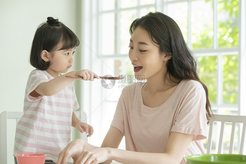 小女孩拿着勺子喂母亲图片