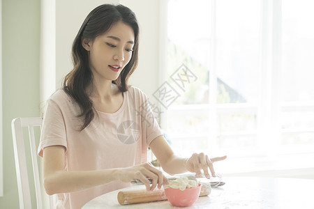 使用擀面杖制作面团的成年女子图片