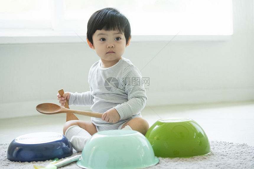 拿着厨具独自玩耍的小男孩图片