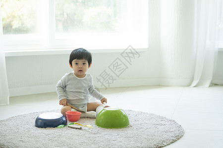 小朋友在客厅地毯上边吃饭边玩耍高清图片