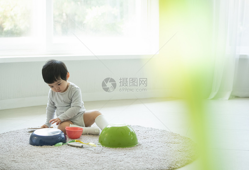 小朋友在客厅地毯上边吃饭边玩耍图片