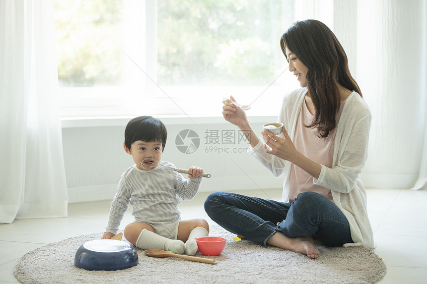 妈妈陪小朋友在客厅地毯上吃饭图片