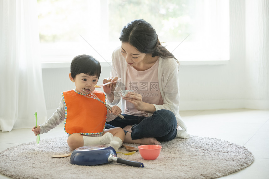 妈妈陪小朋友在客厅地毯上吃饭图片