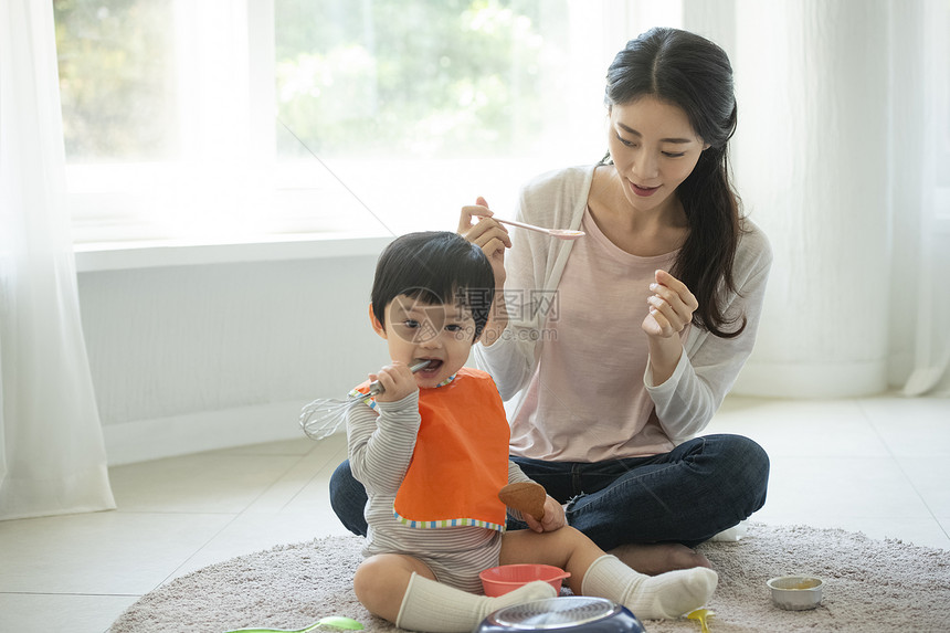 妈妈陪小朋友在客厅地毯上吃饭图片