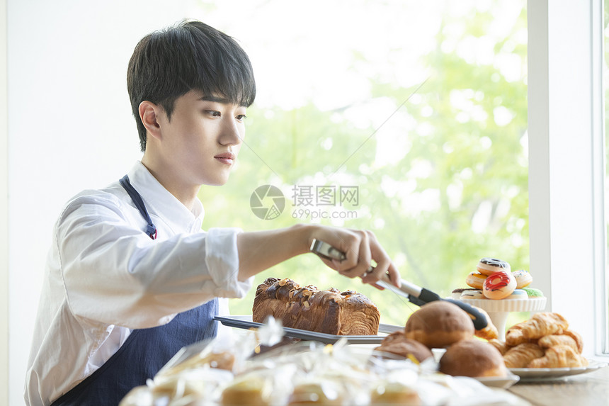 面包店工作夹面包的青年男子图片