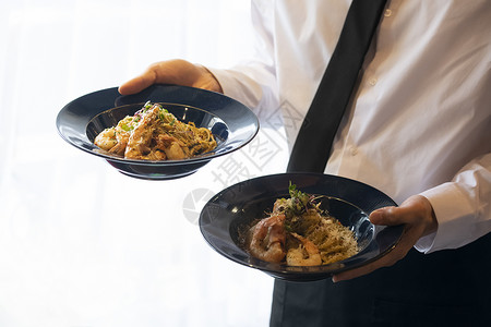 端着餐食的服务员的特写图片