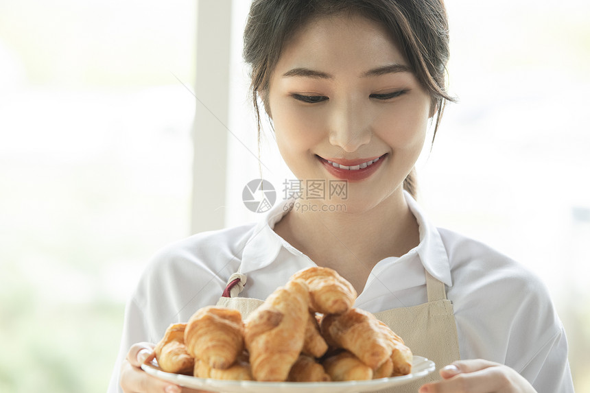 端着一盘面包的青年女子图片