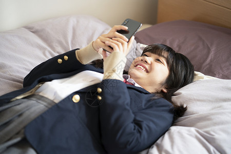 教育高中女生学生躺在床上看智能手机图片