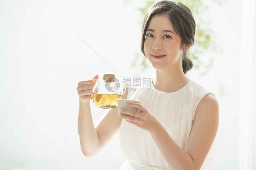 拿着茶壶微笑的青年女子图片