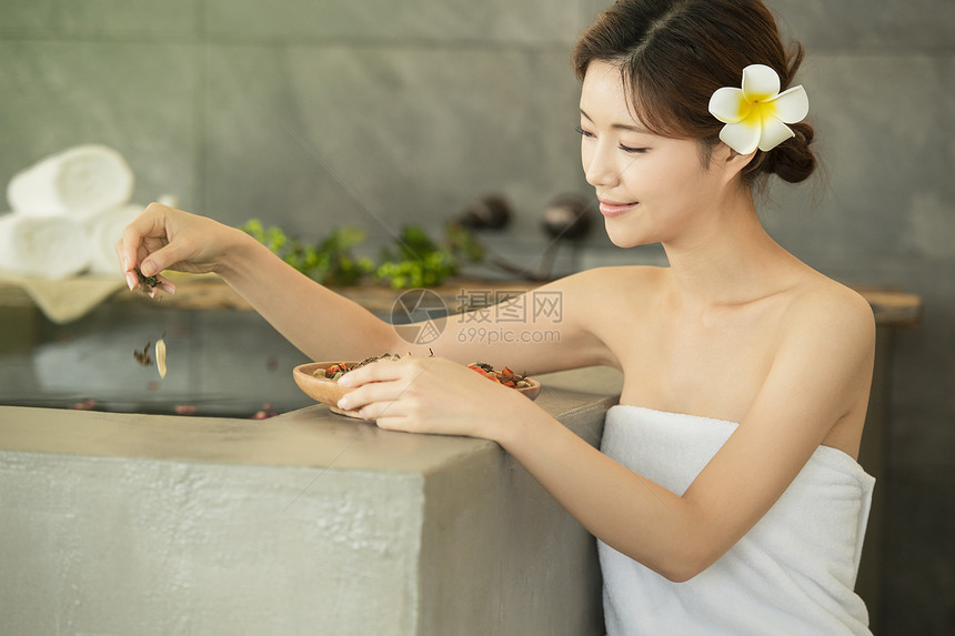浴缸里撒入花瓣的年轻女子图片