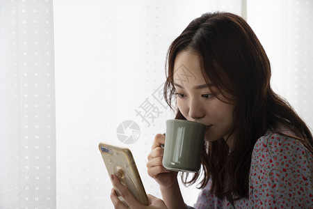 喝咖啡拿着手机的年轻女子图片