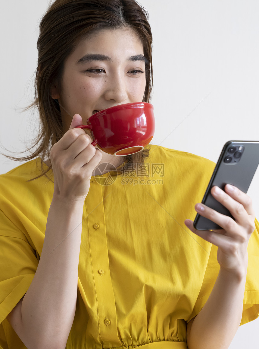 喝咖啡看着手机的年轻女子图片