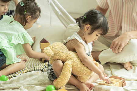 抱着玩具熊玩耍的小女孩背景图片