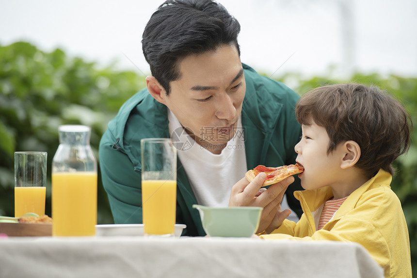 户外野餐喂孩子吃披萨的父亲图片