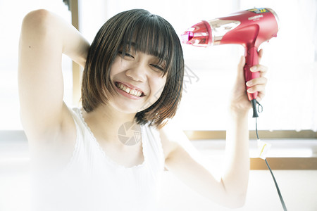 年轻女子拿着吹风机吹头发图片