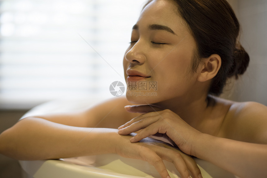 浴缸里泡澡享受的年轻女子图片