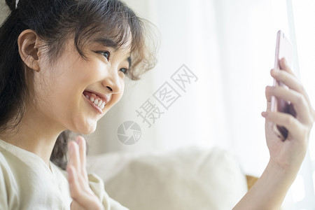 晃动手机素材拿着手机视频通话的年轻女子背景