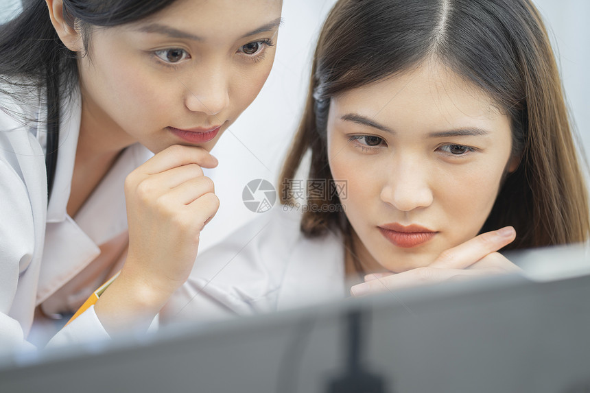 年轻女医生看着电脑思考讨论图片