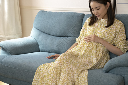沙发上抚摸肚子的孕妇图片