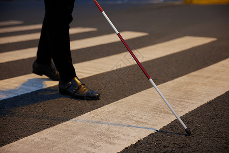 残障人士盲人拿着导盲杖过人行横道特写背景