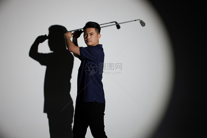 聚光灯下的男运动员打高尔夫球图片