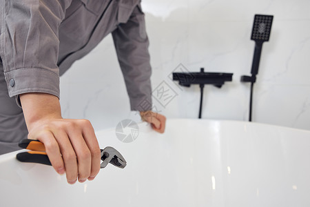 男性维修工检修浴室排水特写图片
