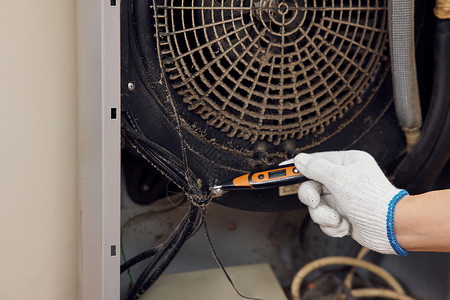 空调使用维修工人使用测电笔检修空调特写背景
