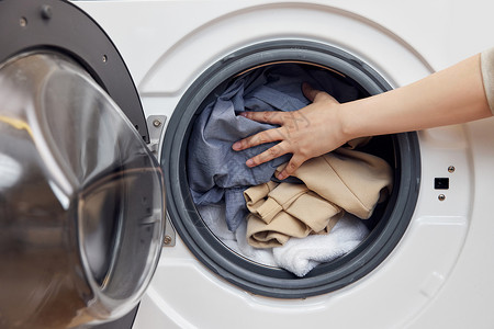 家用好帮手把脏衣物放进滚筒洗衣机特写背景