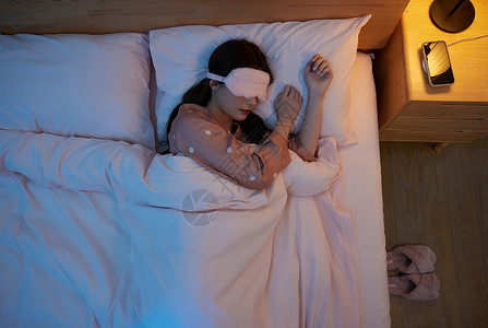 俯拍戴眼罩睡觉的年轻女性高清图片