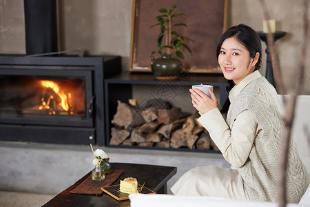 冬季在火炉边取暖喝茶的女性图片