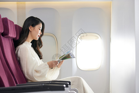 飞机上看书年轻美女飞机上翻阅杂志背景