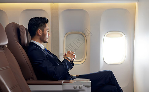 坐飞机旅行商务男士出差坐飞机头等舱看着窗外背景